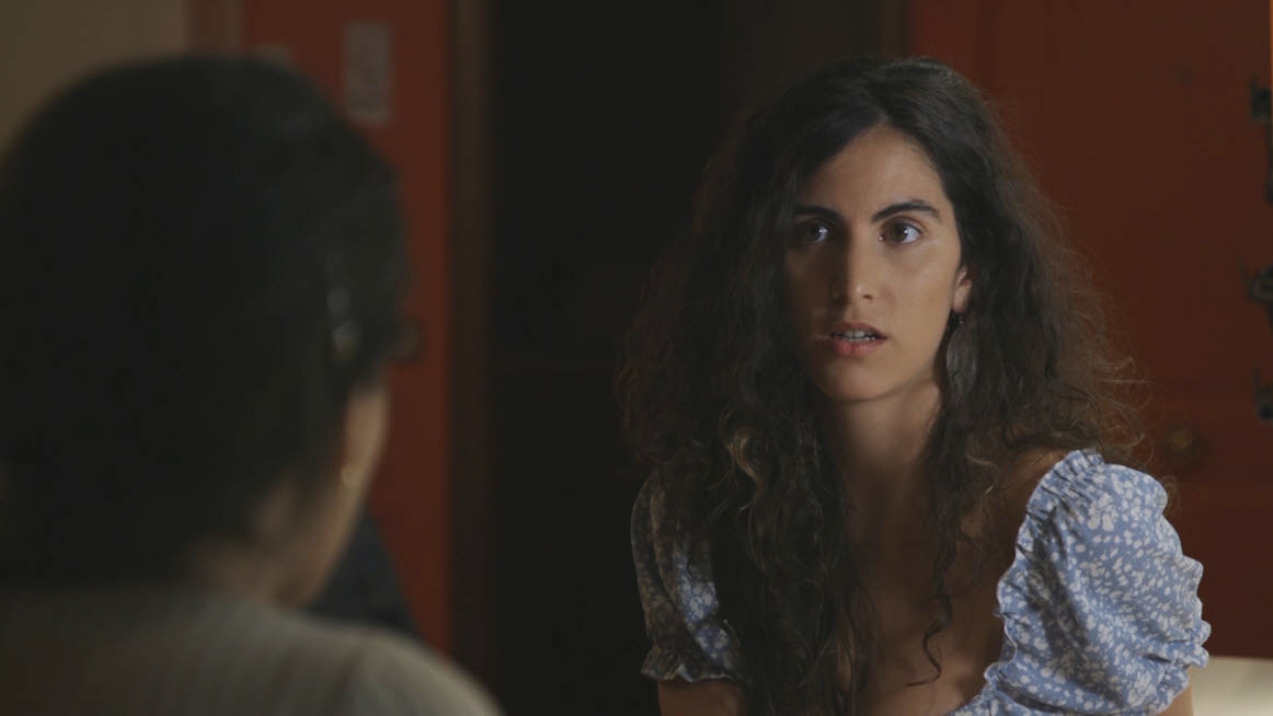 Mujer de pelo rizado mirando con intensidad en una escena dramática de interior