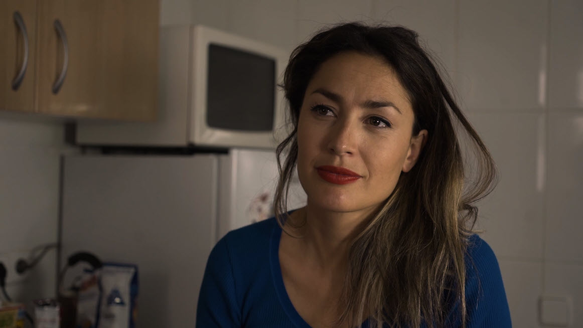 Mujer joven en una cocina con expresión serena en plano medio