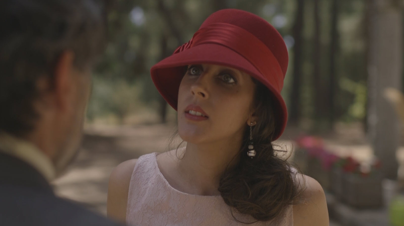 Mujer con sombrero rojo hablando al aire libre en una escena luminosa