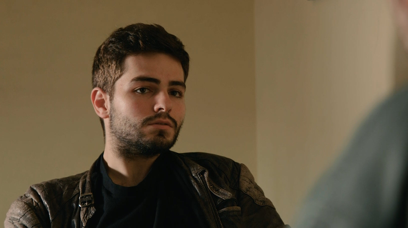 Hombre joven con gesto serio en una escena de interrogatorio