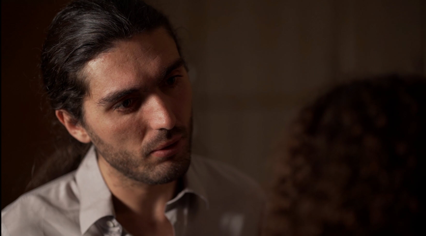 Hombre en conversación intensa iluminado con luz cálida de interior